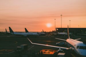 A serene view of parked airplanes at an airport with a beautiful sunset in the background.